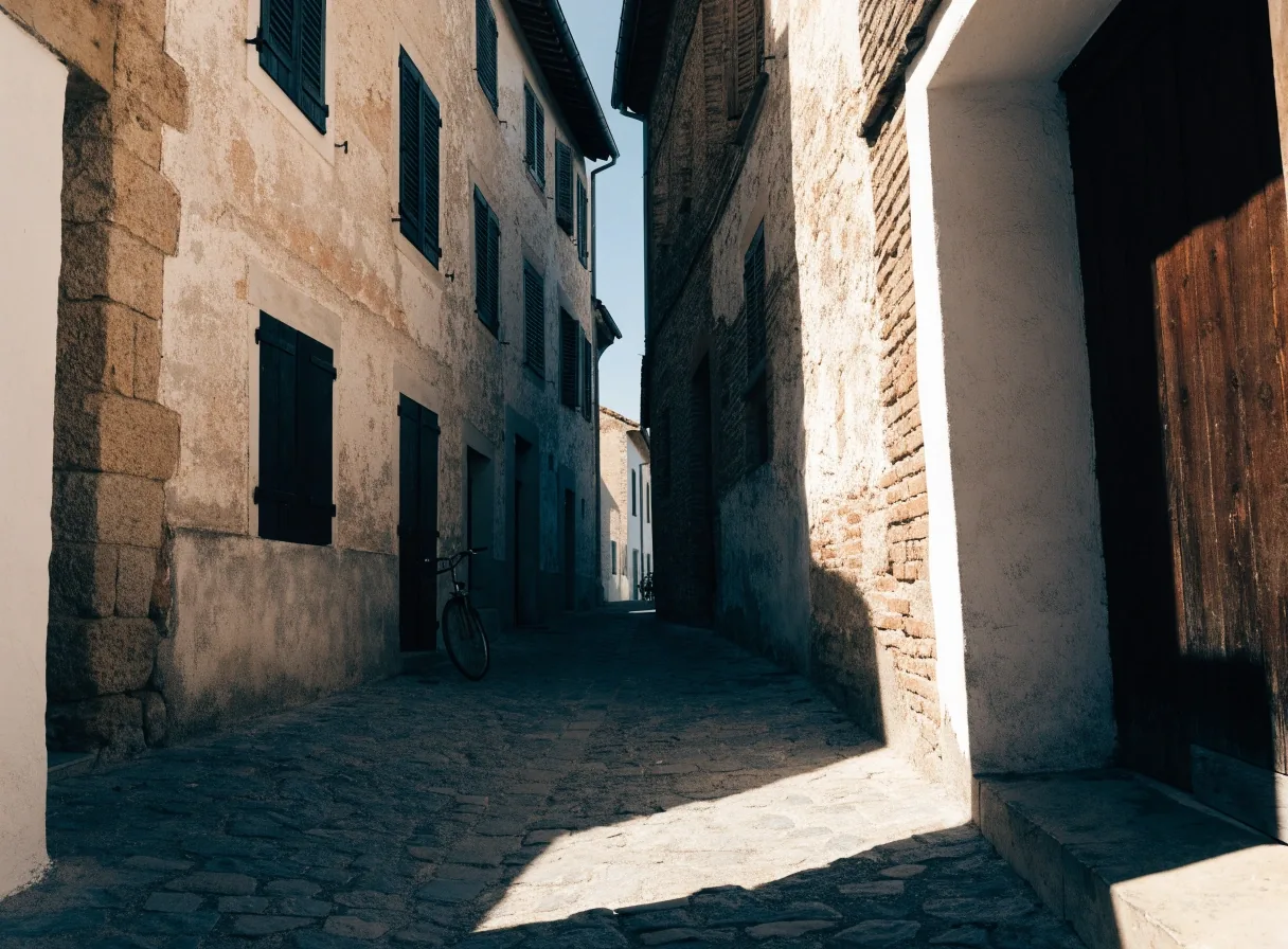 Calle estrecha de un pueblo del interior con fachadas de yeso y una bicicleta apoyada